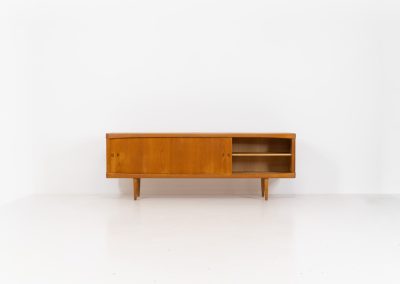Exceptional sideboard by Henry W. Klein for Bramin in oak (Denmark, 1960s). This piece is a true masterpiece of Danish mid-century design. Crafted from high-quality materials, it showcases exquisite attention to detail, from the sculptural integrated handles to the beautifully crafted corner joints. The sideboard offers the perfect balance of aesthetics and functionality. It features two large sliding doors with adjustable shelves behind them and four drawers. The highboard is in very good condition and marked by maker.