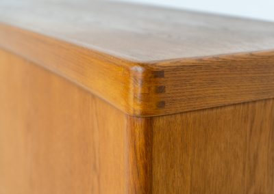 Exceptional sideboard by Henry W. Klein for Bramin in oak (Denmark, 1960s). This piece is a true masterpiece of Danish mid-century design. Crafted from high-quality materials, it showcases exquisite attention to detail, from the sculptural integrated handles to the beautifully crafted corner joints. The sideboard offers the perfect balance of aesthetics and functionality. It features two large sliding doors with adjustable shelves behind them and four drawers. The highboard is in very good condition and marked by maker.