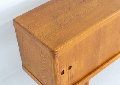 Exceptional sideboard by Henry W. Klein for Bramin in oak (Denmark, 1960s). This piece is a true masterpiece of Danish mid-century design. Crafted from high-quality materials, it showcases exquisite attention to detail, from the sculptural integrated handles to the beautifully crafted corner joints. The sideboard offers the perfect balance of aesthetics and functionality. It features two large sliding doors with adjustable shelves behind them and four drawers. The highboard is in very good condition and marked by maker.