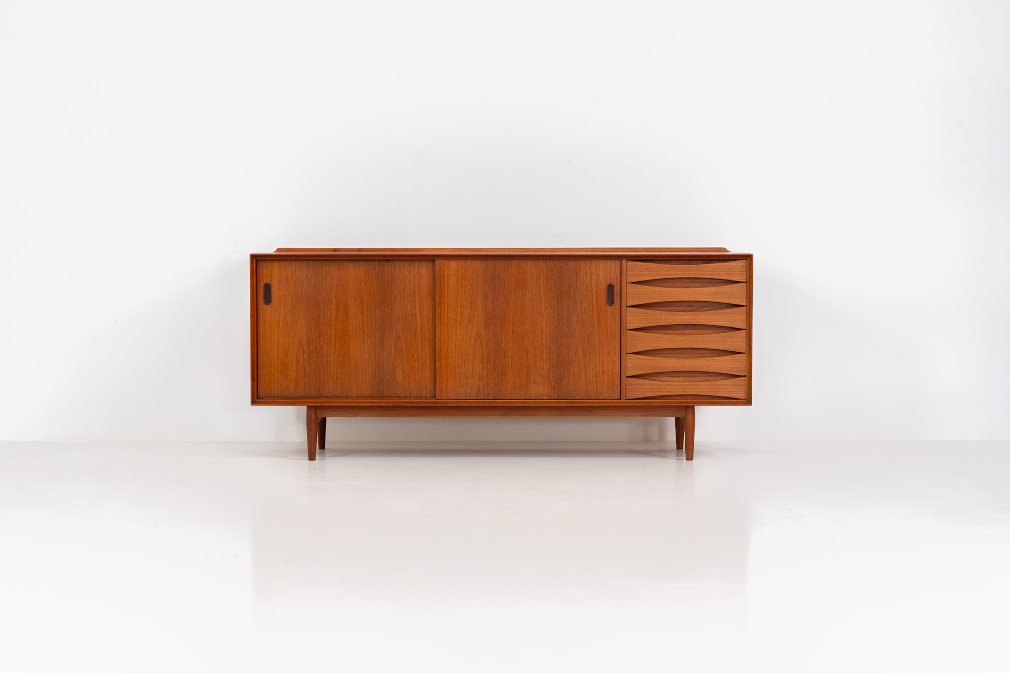 Rare “OS29” sideboard by Arne Vodder for Sibast (Denmark, 1950s). This highly important and collectible masterpiece by Arne Vodder is a rarity to find in good condition. The OS29 has perfect proportions, beautiful aesthetics and a high quality finish. It is crafted out of teak and features a turnable black door, 5 bow tie shaped drawers, adjustable shelves and a raised back edge. This piece remains in very good condition with a few small repair marks and using traces, as shown on the pictures. It is marked and stamped by the maker.