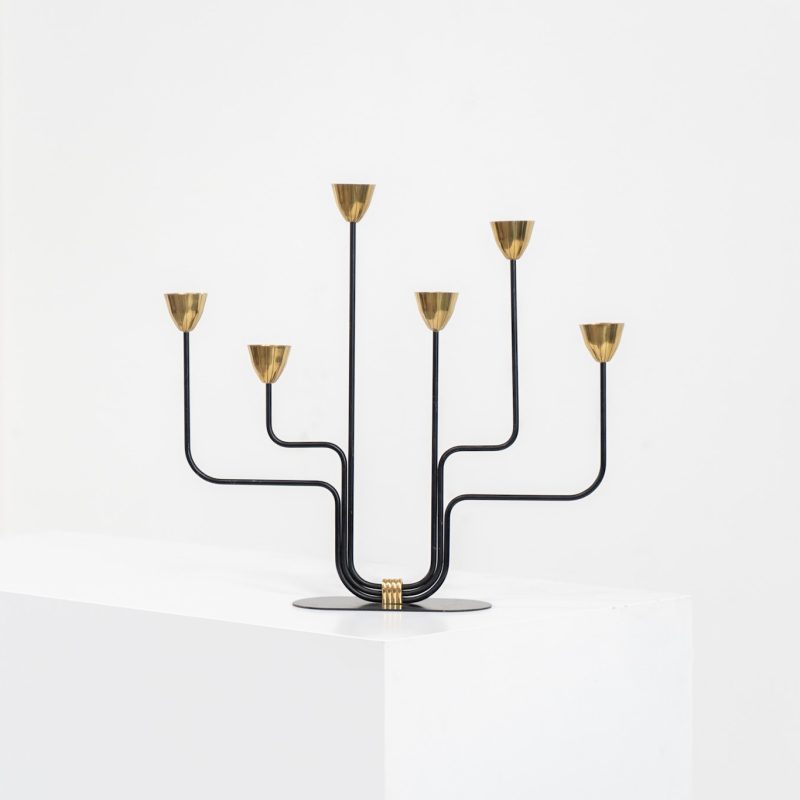 Elegant candelabra in brass and metal by Gunnar Ander for Ystad-Metal (Sweden, 1950s). This refined candelabra features slender, black-lacquered bent metal supports combined with solid brass candle holders, creating a striking contrast. The piece is in very good vintage condition. The brass shows a beautiful, even patina that enhances its character and authenticity. Marked by maker.