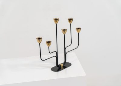 Elegant candelabra in brass and metal by Gunnar Ander for Ystad-Metal (Sweden, 1950s). This refined candelabra features slender, black-lacquered bent metal supports combined with solid brass candle holders, creating a striking contrast. The piece is in very good vintage condition. The brass shows a beautiful, even patina that enhances its character and authenticity. Marked by maker.