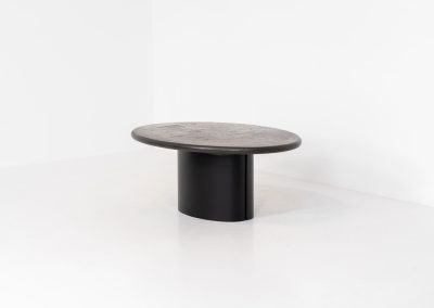 Brutalist coffee table by C. Kneip (Germany, 1990s). A powerful and sculptural brutalist coffee table by German designer C. Kneip, dating from the 1990s. The design is defined by its expressive materiality and architectural presence. The substantial tabletop is crafted from Indian slate and enriched with inlaid elements of lava stone, copper, and brass. These materials are arranged in a richly textured, almost relief-like composition, creating a striking interplay of color, surface, and depth. The heavy stone top is supported by a black lacquered wooden base, providing a sense of grounded solidity. The table is marked by the maker and retains its original certificate. Presented in splendid condition.
