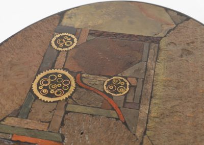 Brutalist coffee table by C. Kneip (Germany, 1990s). A powerful and sculptural brutalist coffee table by German designer C. Kneip, dating from the 1990s. The design is defined by its expressive materiality and architectural presence. The substantial tabletop is crafted from Indian slate and enriched with inlaid elements of lava stone, copper, and brass. These materials are arranged in a richly textured, almost relief-like composition, creating a striking interplay of color, surface, and depth. The heavy stone top is supported by a black lacquered wooden base, providing a sense of grounded solidity. The table is marked by the maker and retains its original certificate. Presented in splendid condition.