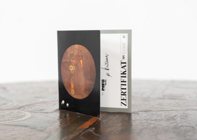 Brutalist coffee table by C. Kneip (Germany, 1990s). A powerful and sculptural brutalist coffee table by German designer C. Kneip, dating from the 1990s. The design is defined by its expressive materiality and architectural presence. The substantial tabletop is crafted from Indian slate and enriched with inlaid elements of lava stone, copper, and brass. These materials are arranged in a richly textured, almost relief-like composition, creating a striking interplay of color, surface, and depth. The heavy stone top is supported by a black lacquered wooden base, providing a sense of grounded solidity. The table is marked by the maker and retains its original certificate. Presented in splendid condition.