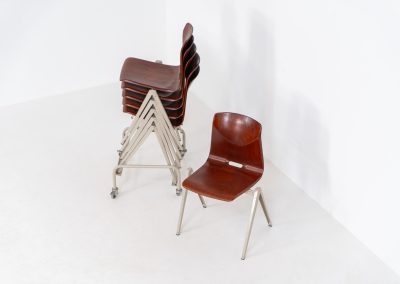 Set of 6 “S22” industrial dining chairs by Elmar Flototto for Pagholz (Germany, 1960s). This set of six original S22 industrial dining chairs, designed by Elmar Flötotto for Pagholz, dates from the 1960s and was produced in Germany. The chairs feature a rare and highly sought-after combination of rosewood-toned moulded Pagholz seats paired with crème powder-coated steel frames. Their clean, functional design reflects the strong industrial aesthetic Pagholz is known for. All chairs are fully stackable and come with the original stacking trolley, a seldom-found and highly desirable addition. The set is in very good vintage condition, showing only minor signs of wear consistent with age and use, without structural issues. A timeless and characterful set, suitable for both dining and contract interiors, and a strong example of post-war German industrial design.