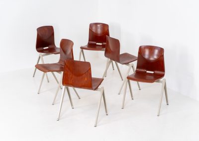 Set of 6 “S22” industrial dining chairs by Elmar Flototto for Pagholz (Germany, 1960s). This set of six original S22 industrial dining chairs, designed by Elmar Flötotto for Pagholz, dates from the 1960s and was produced in Germany. The chairs feature a rare and highly sought-after combination of rosewood-toned moulded Pagholz seats paired with crème powder-coated steel frames. Their clean, functional design reflects the strong industrial aesthetic Pagholz is known for. All chairs are fully stackable and come with the original stacking trolley, a seldom-found and highly desirable addition. The set is in very good vintage condition, showing only minor signs of wear consistent with age and use, without structural issues. A timeless and characterful set, suitable for both dining and contract interiors, and a strong example of post-war German industrial design.