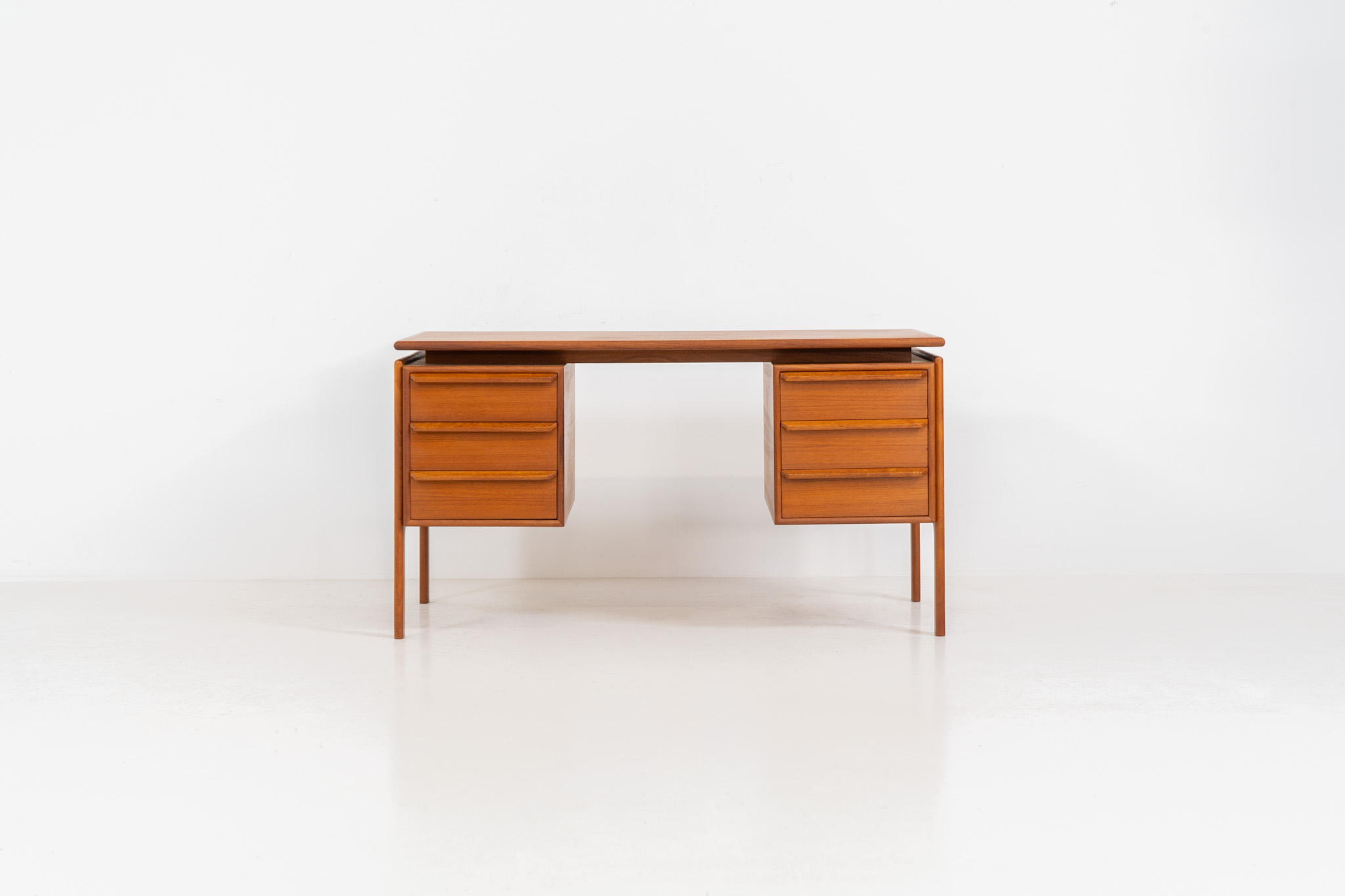 Teak writing desk by Arne Vodder for G.V. Møbler (Denmark, 1960s). This exceptionally beautiful piece is a true example of top-quality Danish craftsmanship. Made from teak, it showcases elegant aesthetics with softly rounded edges and a floating desk top. It contains six very deep drawers and a finished backside, making it an ideal piece for placement in the center of a room. The desk is in excellent condition.