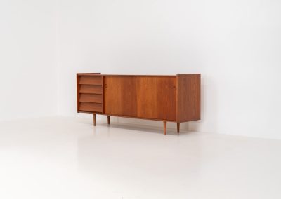 Teak sideboard by Nils Jonsson for Hugo Troeds (Sweden, 1950s). Elegant sideboard by Swedish designer Nils Jonsson, executed in warm teak. The clean, architectural form is complemented by tapered legs and balanced proportions. A distinctive feature of this piece is the set of sculpted, stepped drawers, offering both visual rhythm and practical storage. Sliding doors reveal generous interior space, making the sideboard as functional as it is refined. A timeless example of Scandinavian modern design, presented in excellent vintage condition.