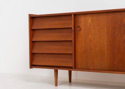 Teak sideboard by Nils Jonsson for Hugo Troeds (Sweden, 1950s). Elegant sideboard by Swedish designer Nils Jonsson, executed in warm teak. The clean, architectural form is complemented by tapered legs and balanced proportions. A distinctive feature of this piece is the set of sculpted, stepped drawers, offering both visual rhythm and practical storage. Sliding doors reveal generous interior space, making the sideboard as functional as it is refined. A timeless example of Scandinavian modern design, presented in excellent vintage condition.
