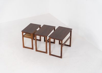 “Model 219” nesting tables by Johannes Andersen & Illum Wickelso for CFC Silkeborg (Denmark, 1960s). These tables are crafted from rosewood and feature a sleek and functional design, allowing them to nest seamlessly within one another. They offer amazing details like the rattan magazine shelf, the mesmerizing woodgrain and the stunning wood connections Versatile and stylish, they serve perfectly as side tables or coffee tables, adapting effortlessly to various interior settings. All three tables are in mint condition. Marked by maker.