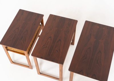 “Model 219” nesting tables by Johannes Andersen & Illum Wickelso for CFC Silkeborg (Denmark, 1960s). These tables are crafted from rosewood and feature a sleek and functional design, allowing them to nest seamlessly within one another. They offer amazing details like the rattan magazine shelf, the mesmerizing woodgrain and the stunning wood connections Versatile and stylish, they serve perfectly as side tables or coffee tables, adapting effortlessly to various interior settings. All three tables are in mint condition. Marked by maker.
