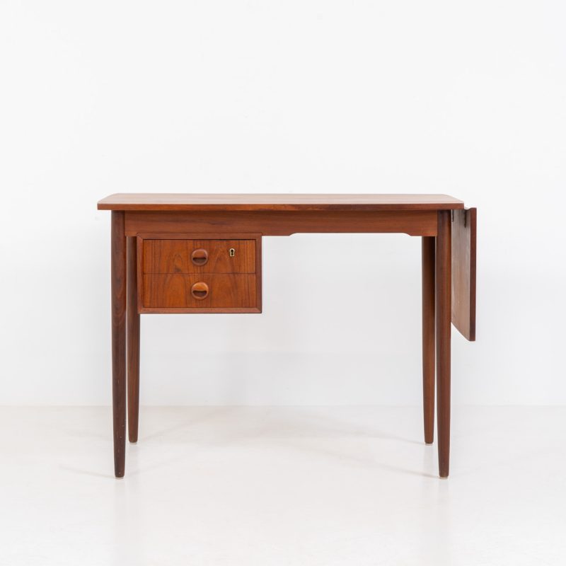 Stunning free standing drop-leaf desk in teak (Denmark, 1960s). It features a cabinet with two drawers and a convenient drop-leaf to add extra space. This writing desk presents itself in good condition!