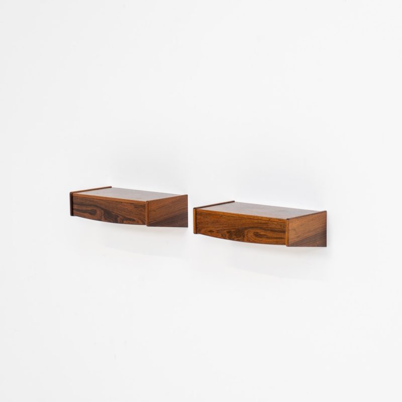 Pair of floating bedside tables in rosewood (Denmark, 1960s). This beautiful pair of bedside tables is easily mounted to the wall and contains a small drawer. They offer a minimalist appearance and a beautiful woodgrain. In very good condition with minimal traces of use visible.