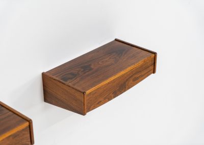 Pair of floating bedside tables in rosewood (Denmark, 1960s). This beautiful pair of bedside tables is easily mounted to the wall and contains a small drawer. They offer a minimalist appearance and a beautiful woodgrain. In very good condition with minimal traces of use visible.