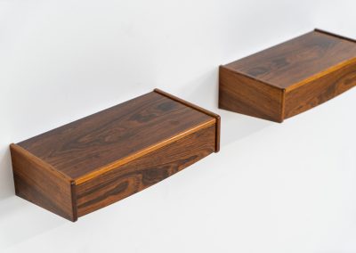 Pair of floating bedside tables in rosewood (Denmark, 1960s). This beautiful pair of bedside tables is easily mounted to the wall and contains a small drawer. They offer a minimalist appearance and a beautiful woodgrain. In very good condition with minimal traces of use visible.