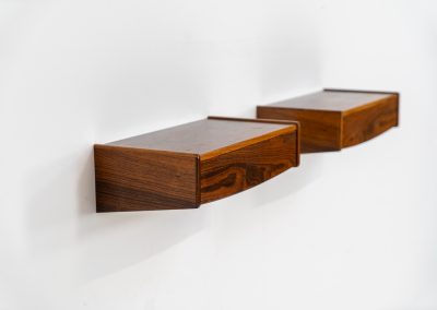 Pair of floating bedside tables in rosewood (Denmark, 1960s). This beautiful pair of bedside tables is easily mounted to the wall and contains a small drawer. They offer a minimalist appearance and a beautiful woodgrain. In very good condition with minimal traces of use visible.