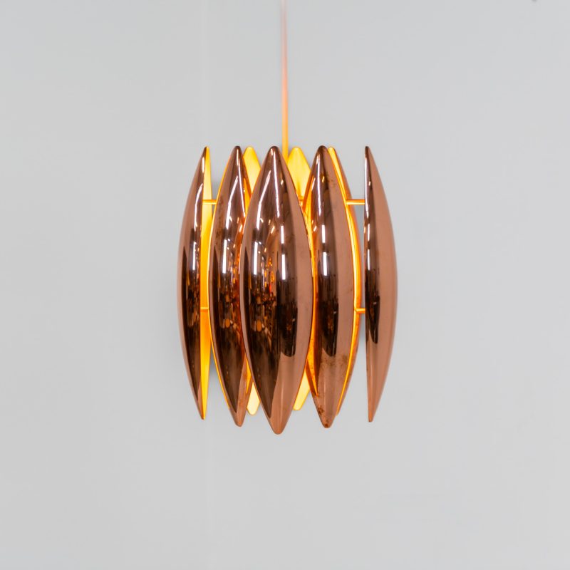 A rare copper version of the “Kastor” pendel by Jo Hammerborg for Fog & Mørup (Denmark, 1960s). An iconic example of Scandinavian modernism! This exceptional high-end piece is constructed from layered copper shells, elegantly separated by brass spacers, offering a spectacular sculptural presence. The interior is lacquered in orange, creating a warm and atmospheric glow. When illuminated, the lamp disperses light beautifully and projects a subtle star-like pattern onto the ceiling. One of Hammerborg's most striking and refined designs remaining in excellent condition, with only a light natural patina to the copper.