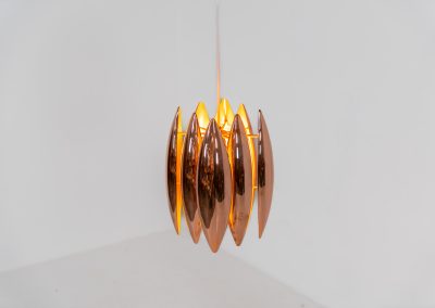 A rare copper version of the “Kastor” pendel by Jo Hammerborg for Fog & Mørup (Denmark, 1960s). An iconic example of Scandinavian modernism! This exceptional high-end piece is constructed from layered copper shells, elegantly separated by brass spacers, offering a spectacular sculptural presence. The interior is lacquered in orange, creating a warm and atmospheric glow. When illuminated, the lamp disperses light beautifully and projects a subtle star-like pattern onto the ceiling. One of Hammerborg's most striking and refined designs remaining in excellent condition, with only a light natural patina to the copper.