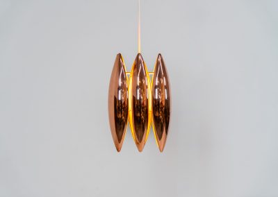 A rare copper version of the “Kastor” pendel by Jo Hammerborg for Fog & Mørup (Denmark, 1960s). An iconic example of Scandinavian modernism! This exceptional high-end piece is constructed from layered copper shells, elegantly separated by brass spacers, offering a spectacular sculptural presence. The interior is lacquered in orange, creating a warm and atmospheric glow. When illuminated, the lamp disperses light beautifully and projects a subtle star-like pattern onto the ceiling. One of Hammerborg's most striking and refined designs remaining in excellent condition, with only a light natural patina to the copper.