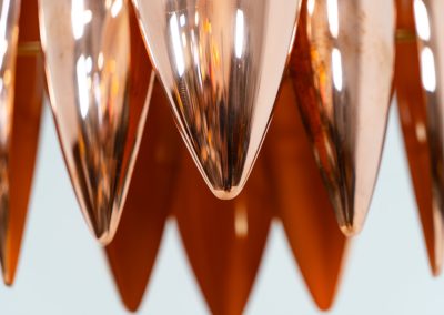 A rare copper version of the “Kastor” pendel by Jo Hammerborg for Fog & Mørup (Denmark, 1960s). An iconic example of Scandinavian modernism! This exceptional high-end piece is constructed from layered copper shells, elegantly separated by brass spacers, offering a spectacular sculptural presence. The interior is lacquered in orange, creating a warm and atmospheric glow. When illuminated, the lamp disperses light beautifully and projects a subtle star-like pattern onto the ceiling. One of Hammerborg's most striking and refined designs remaining in excellent condition, with only a light natural patina to the copper.