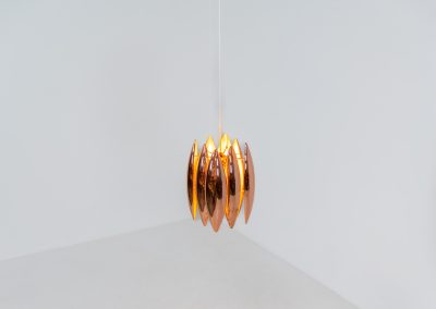 A rare copper version of the “Kastor” pendel by Jo Hammerborg for Fog & Mørup (Denmark, 1960s). An iconic example of Scandinavian modernism! This exceptional high-end piece is constructed from layered copper shells, elegantly separated by brass spacers, offering a spectacular sculptural presence. The interior is lacquered in orange, creating a warm and atmospheric glow. When illuminated, the lamp disperses light beautifully and projects a subtle star-like pattern onto the ceiling. One of Hammerborg's most striking and refined designs remaining in excellent condition, with only a light natural patina to the copper.