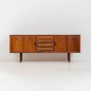 Extremely rare sideboard in rosewood by Svend Aage Larsen for Faarup (Denmark, 1950s). A rare and refined sideboard designed by Svend Aage Larsen and produced by Faarup in the 1950s. The façade is defined by two elegantly crafted tambour sliding doors, complemented by four drawers with beautifully inset handles. The interior layout offers generous and well-organized storage. Executed in richly figured Brazilian rosewood, the cabinet displays a deep and dynamic grain pattern, highlighting the exceptional timber selection and craftsmanship of the period. The piece presents in excellent vintage condition, with only minor age-related wear consistent with its history.