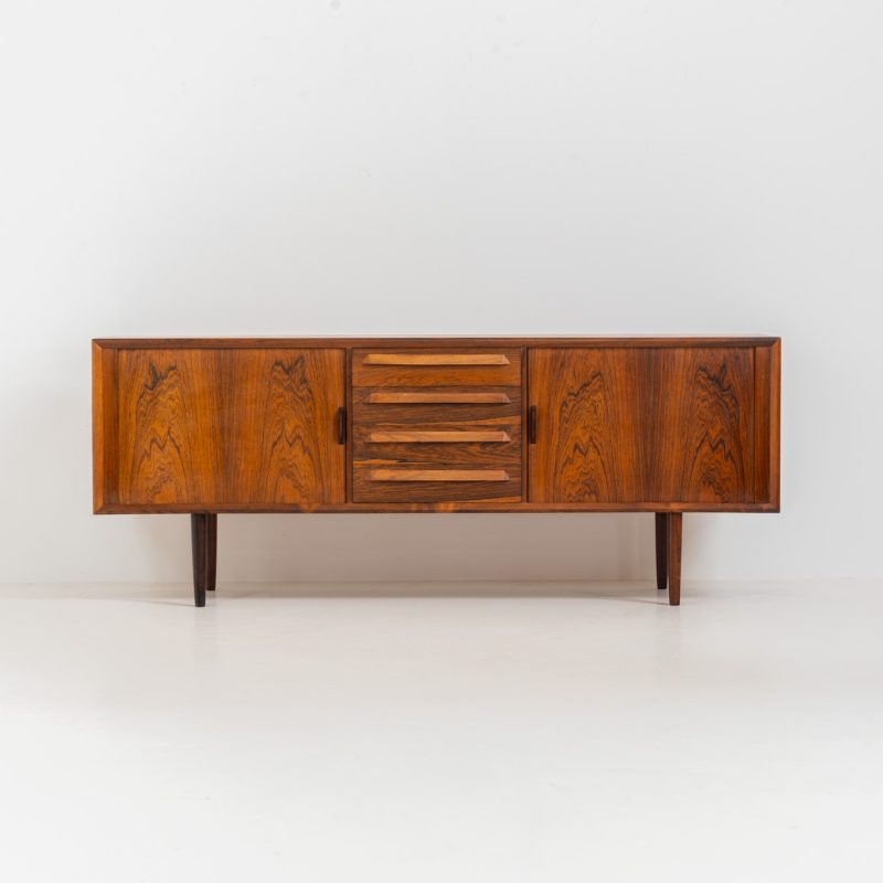 Extremely rare sideboard in rosewood by Svend Aage Larsen for Faarup (Denmark, 1950s). A rare and refined sideboard designed by Svend Aage Larsen and produced by Faarup in the 1950s. The façade is defined by two elegantly crafted tambour sliding doors, complemented by four drawers with beautifully inset handles. The interior layout offers generous and well-organized storage. Executed in richly figured Brazilian rosewood, the cabinet displays a deep and dynamic grain pattern, highlighting the exceptional timber selection and craftsmanship of the period. The piece presents in excellent vintage condition, with only minor age-related wear consistent with its history.