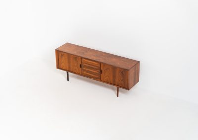 Extremely rare sideboard in rosewood by Svend Aage Larsen for Faarup (Denmark, 1950s). A rare and refined sideboard designed by Svend Aage Larsen and produced by Faarup in the 1950s. The façade is defined by two elegantly crafted tambour sliding doors, complemented by four drawers with beautifully inset handles. The interior layout offers generous and well-organized storage. Executed in richly figured Brazilian rosewood, the cabinet displays a deep and dynamic grain pattern, highlighting the exceptional timber selection and craftsmanship of the period. The piece presents in excellent vintage condition, with only minor age-related wear consistent with its history.