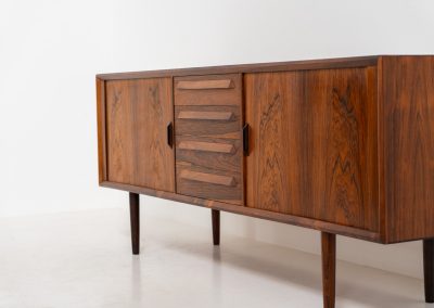 Extremely rare sideboard in rosewood by Svend Aage Larsen for Faarup (Denmark, 1950s). A rare and refined sideboard designed by Svend Aage Larsen and produced by Faarup in the 1950s. The façade is defined by two elegantly crafted tambour sliding doors, complemented by four drawers with beautifully inset handles. The interior layout offers generous and well-organized storage. Executed in richly figured Brazilian rosewood, the cabinet displays a deep and dynamic grain pattern, highlighting the exceptional timber selection and craftsmanship of the period. The piece presents in excellent vintage condition, with only minor age-related wear consistent with its history.
