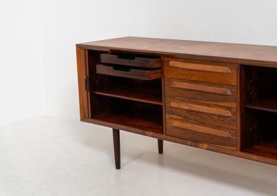 Extremely rare sideboard in rosewood by Svend Aage Larsen for Faarup (Denmark, 1950s). A rare and refined sideboard designed by Svend Aage Larsen and produced by Faarup in the 1950s. The façade is defined by two elegantly crafted tambour sliding doors, complemented by four drawers with beautifully inset handles. The interior layout offers generous and well-organized storage. Executed in richly figured Brazilian rosewood, the cabinet displays a deep and dynamic grain pattern, highlighting the exceptional timber selection and craftsmanship of the period. The piece presents in excellent vintage condition, with only minor age-related wear consistent with its history.