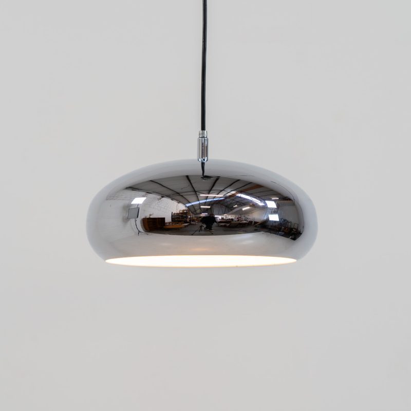 Chrome pendel by Richard Carruters for Ateljé Lyktan (Sweden, 1970s). A sleek and contemporary lamp that perfectly captures the space-age aesthetic of the mid-century era. The high-gloss chrome finish creates a striking mirror effect, reflecting the surrounding interior, while the wide, shallow dome provides a focused yet warm downward glow. The lamp is in amazing condition with some age related wear on the the chrome and the inside lacquer.