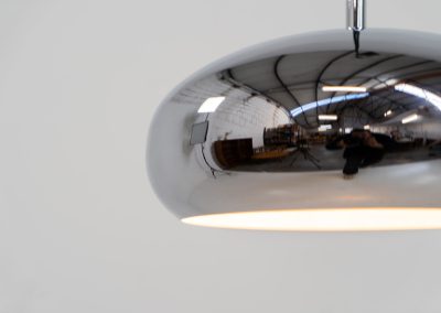 Chrome pendel by Richard Carruters for Ateljé Lyktan (Sweden, 1970s). A sleek and contemporary lamp that perfectly captures the space-age aesthetic of the mid-century era. The high-gloss chrome finish creates a striking mirror effect, reflecting the surrounding interior, while the wide, shallow dome provides a focused yet warm downward glow. The lamp is in amazing condition with some age related wear on the the chrome and the inside lacquer.