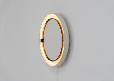 Model A41 backlit wall mirror by Allibert (Germany, 1970s). A striking space age design by Allibert, Germany. This Model A41 mirror is crafted from molded plastic and designed to hold four E14 bulbs inside, operated by a pull switch on the side. When illuminated, the translucent plastic frame softly diffuses the light, creating a warm halo effect around the mirror glass. The mirror can be tilted up or down, adding both functionality and a sculptural presence to the piece. Presented in good vintage condition with light, age-appropriate wear.