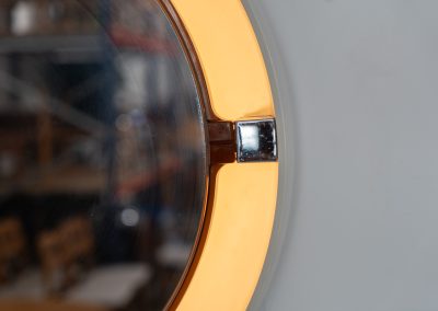 Model A41 backlit wall mirror by Allibert (Germany, 1970s). A striking space age design by Allibert, Germany. This Model A41 mirror is crafted from molded plastic and designed to hold four E14 bulbs inside, operated by a pull switch on the side. When illuminated, the translucent plastic frame softly diffuses the light, creating a warm halo effect around the mirror glass. The mirror can be tilted up or down, adding both functionality and a sculptural presence to the piece. Presented in good vintage condition with light, age-appropriate wear.