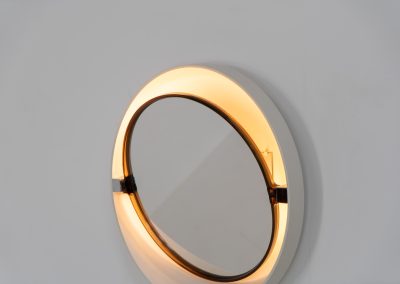 Model A41 backlit wall mirror by Allibert (Germany, 1970s). A striking space age design by Allibert, Germany. This Model A41 mirror is crafted from molded plastic and designed to hold four E14 bulbs inside, operated by a pull switch on the side. When illuminated, the translucent plastic frame softly diffuses the light, creating a warm halo effect around the mirror glass. The mirror can be tilted up or down, adding both functionality and a sculptural presence to the piece. Presented in good vintage condition with light, age-appropriate wear.