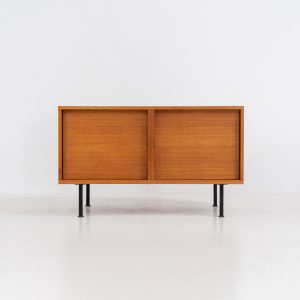 Minimalist cabinet by Gunter Renkel for Rego (Germany, 1960s). Crafted in warm teak, the cabinet features clean architectural lines, two doors, and a beautifully balanced composition. The slender black metal legs create a subtle contrast and give the piece a light, elevated appearance. Compact yet versatile, it works perfectly as a low sideboard, media cabinet, or storage unit in both modern and mid-century interiors. Its in very good vintage condition. Make sure to check out the dimensions as it’s slightly deeper than your average cabinet.