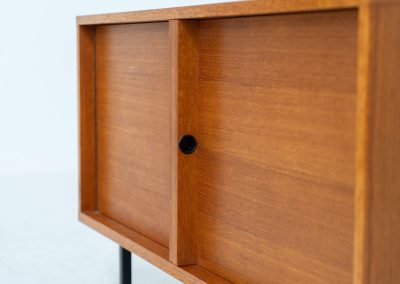 Minimalist cabinet by Gunter Renkel for Rego (Germany, 1960s). Crafted in warm teak, the cabinet features clean architectural lines, two doors, and a beautifully balanced composition. The slender black metal legs create a subtle contrast and give the piece a light, elevated appearance. Compact yet versatile, it works perfectly as a low sideboard, media cabinet, or storage unit in both modern and mid-century interiors. Its in very good vintage condition. Make sure to check out the dimensions as it’s slightly deeper than your average cabinet.