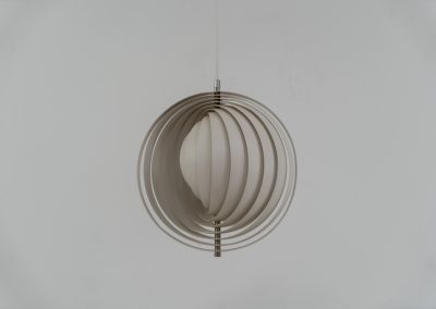 A wonderful example of an early “Moon” pendant light by Verner Panton for Louis Poulsen (Denmark, 1960s). An early model of the iconic Space Age "moon lamp," also known as the Visor pendant, designed by Verner Panton in the 1960s and produced by Louis Poulsen, Denmark. This sculptural piece features ten white, rotatable rings made of enameled metal, arranged around a central light source. The adjustable blades allow for subtle variation in light diffusion, creating a warm, atmospheric glow while maintaining its striking geometric presence. A true Danish Op-Art design classic, the lamp combines functionality with a bold visual identity that remains timeless. The lamp is in very good vintage condition with some minor scuffs in the paint.