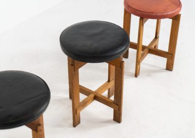 Very rare set of stools by Uno & Östen Kristiansson for Luxus Vittsjö (Sweden, 1950s). A highly collectible find, designed by the renowned brothers Uno & Östen Kristiansson and a true masterclass in Scandinavian architectural furniture. They consist of a solid oak cross-shaped base and a round leather seat, two in black and one in red. They are in used vintage condition with a nice patina on the seats and visible using traces on the wood. The two black stools can be sold separately upon request.