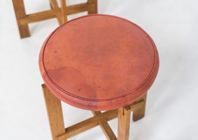 Very rare set of stools by Uno & Östen Kristiansson for Luxus Vittsjö (Sweden, 1950s). A highly collectible find, designed by the renowned brothers Uno & Östen Kristiansson and a true masterclass in Scandinavian architectural furniture. They consist of a solid oak cross-shaped base and a round leather seat, two in black and one in red. They are in used vintage condition with a nice patina on the seats and visible using traces on the wood. The two black stools can be sold separately upon request.