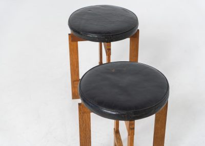 Very rare set of stools by Uno & Östen Kristiansson for Luxus Vittsjö (Sweden, 1950s). A highly collectible find, designed by the renowned brothers Uno & Östen Kristiansson and a true masterclass in Scandinavian architectural furniture. They consist of a solid oak cross-shaped base and a round leather seat, two in black and one in red. They are in used vintage condition with a nice patina on the seats and visible using traces on the wood. The two black stools can be sold separately upon request.