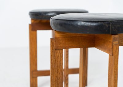 Very rare set of stools by Uno & Östen Kristiansson for Luxus Vittsjö (Sweden, 1950s). A highly collectible find, designed by the renowned brothers Uno & Östen Kristiansson and a true masterclass in Scandinavian architectural furniture. They consist of a solid oak cross-shaped base and a round leather seat, two in black and one in red. They are in used vintage condition with a nice patina on the seats and visible using traces on the wood. The two black stools can be sold separately upon request.