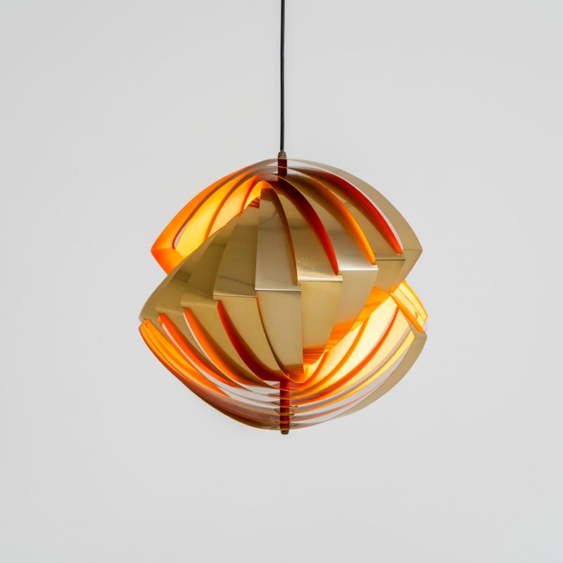 “Konkylie” pendant light by Louis Weisdorf for Lyfa (Denmark, 1960s). A strong, sculptural design with a clear architectural feel, typical of Weisdorf’s work. The layered brass shades unfold like a shell, revealing a striking red and orange interior that adds depth and warmth. When lit, the light is softly diffused, creating a rich, atmospheric glow with subtle color reflection. The interplay between the polished brass exterior and the warm-toned interior gives the piece a dynamic character. A well-balanced design that works just as well as a statement piece above a dining table as it does in a more minimal setting. A solid example of Danish mid-century lighting, where form and function meet effortlessly.
