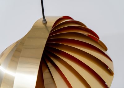 “Konkylie” pendant light by Louis Weisdorf for Lyfa (Denmark, 1960s). A strong, sculptural design with a clear architectural feel, typical of Weisdorf’s work. The layered brass shades unfold like a shell, revealing a striking red and orange interior that adds depth and warmth. When lit, the light is softly diffused, creating a rich, atmospheric glow with subtle color reflection. The interplay between the polished brass exterior and the warm-toned interior gives the piece a dynamic character. A well-balanced design that works just as well as a statement piece above a dining table as it does in a more minimal setting. A solid example of Danish mid-century lighting, where form and function meet effortlessly.