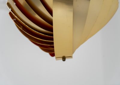 “Konkylie” pendant light by Louis Weisdorf for Lyfa (Denmark, 1960s). A strong, sculptural design with a clear architectural feel, typical of Weisdorf’s work. The layered brass shades unfold like a shell, revealing a striking red and orange interior that adds depth and warmth. When lit, the light is softly diffused, creating a rich, atmospheric glow with subtle color reflection. The interplay between the polished brass exterior and the warm-toned interior gives the piece a dynamic character. A well-balanced design that works just as well as a statement piece above a dining table as it does in a more minimal setting. A solid example of Danish mid-century lighting, where form and function meet effortlessly.