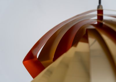 “Konkylie” pendant light by Louis Weisdorf for Lyfa (Denmark, 1960s). A strong, sculptural design with a clear architectural feel, typical of Weisdorf’s work. The layered brass shades unfold like a shell, revealing a striking red and orange interior that adds depth and warmth. When lit, the light is softly diffused, creating a rich, atmospheric glow with subtle color reflection. The interplay between the polished brass exterior and the warm-toned interior gives the piece a dynamic character. A well-balanced design that works just as well as a statement piece above a dining table as it does in a more minimal setting. A solid example of Danish mid-century lighting, where form and function meet effortlessly.