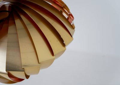 “Konkylie” pendant light by Louis Weisdorf for Lyfa (Denmark, 1960s). A strong, sculptural design with a clear architectural feel, typical of Weisdorf’s work. The layered brass shades unfold like a shell, revealing a striking red and orange interior that adds depth and warmth. When lit, the light is softly diffused, creating a rich, atmospheric glow with subtle color reflection. The interplay between the polished brass exterior and the warm-toned interior gives the piece a dynamic character. A well-balanced design that works just as well as a statement piece above a dining table as it does in a more minimal setting. A solid example of Danish mid-century lighting, where form and function meet effortlessly.