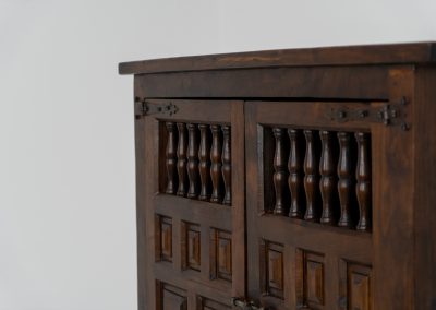 Stunning Spanish brutalist cabinet, 1950s. Striking and architectural, this 1950s Spanish cabinet is a powerful example of brutalist craftsmanship. Executed in solid wood, it features a deeply carved geometric façade with repetitive panel motifs that create a strong sense of rhythm and depth. The upper doors are accented with turned spindle details, adding contrast to the otherwise bold and graphic design. Original iron hardware, including hinges and latches, reinforces its rustic character. Behind the doors, the cabinet offers generous storage, making it as functional as it is sculptural. The warm patina of the wood enhances its presence, giving it a timeless, almost monolithic feel.