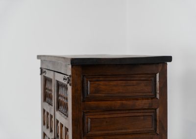 Stunning Spanish brutalist cabinet, 1950s. Striking and architectural, this 1950s Spanish cabinet is a powerful example of brutalist craftsmanship. Executed in solid wood, it features a deeply carved geometric façade with repetitive panel motifs that create a strong sense of rhythm and depth. The upper doors are accented with turned spindle details, adding contrast to the otherwise bold and graphic design. Original iron hardware, including hinges and latches, reinforces its rustic character. Behind the doors, the cabinet offers generous storage, making it as functional as it is sculptural. The warm patina of the wood enhances its presence, giving it a timeless, almost monolithic feel.